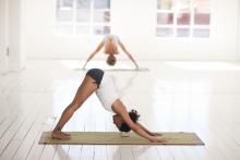 Two women doing yoga -- one in foreground is doing downward-facing dog